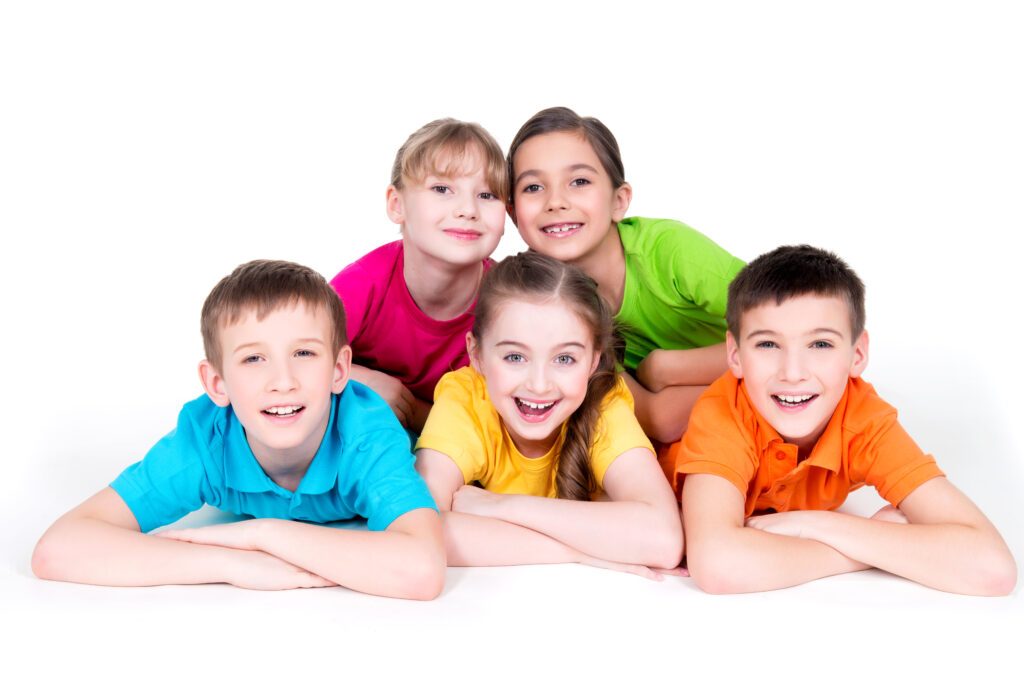 Five beautiful smiling kids lying on the floor in bright colorful t-shirts -  isolated on white.